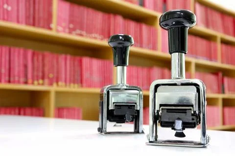 Self-inking, rubber date stamp on the table. background of shelves with books  Stock Photos