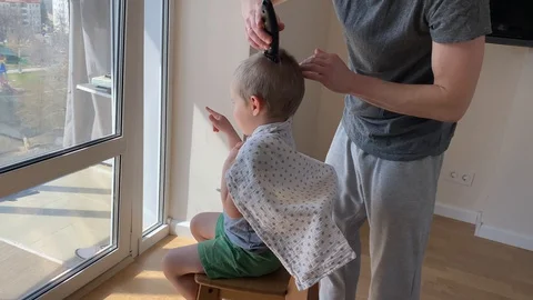 Self-isolation concept. Father cutting the hair of a little son Stock Footage 129147235