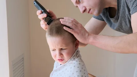 Self-isolation concept. Father cutting the hair of a little son with a hair Stock Footage 129148359