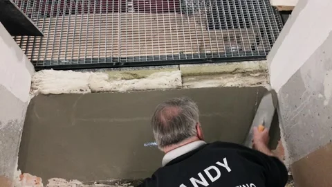 Self-leveling compound apply on the floor by a worker on his knees, over Vídeos de archivo 153483834