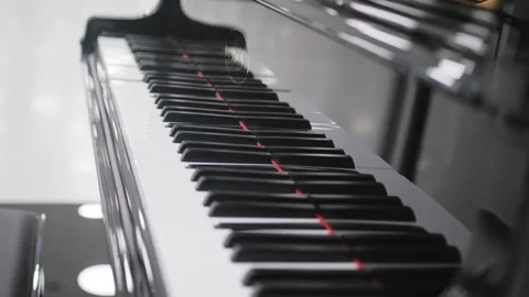 Self playing piano performs musical melody in lit hall Vídeos de archivo 243812043
