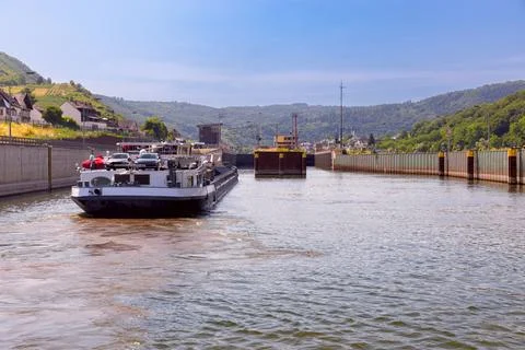 A self-propelled cargo ship goes along the Moselle River on a clear sunny day Stock Photos