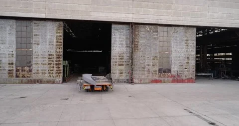 A self-propelled modular transporter drives out of the factory gate and carries Video stock 315759675