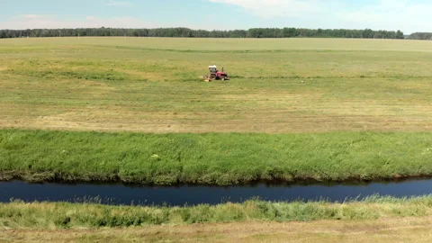 Self-propelled mower harvests hay for livestock feed in the summer in a meadow Stock Footage 136649840