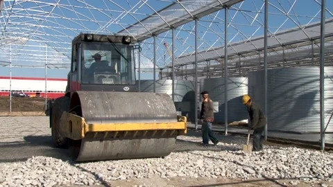 Self-propelled road roller compacts and levels loose soil in greenhouse. Stock Footage 152473133