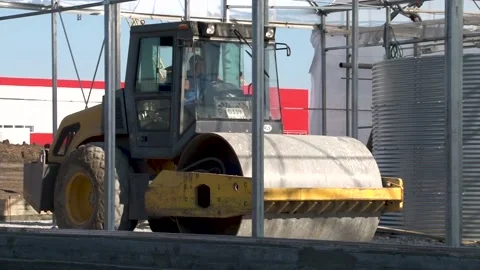 Self-propelled road roller compacts and levels loose soil in greenhouse. Stock Footage 152473205