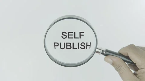 Self Publish text or word highlighted by a magnifying glass in a hand Stock Footage 303709753