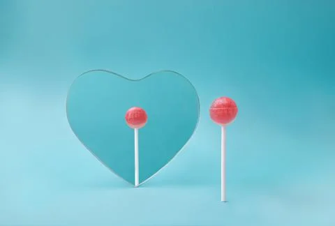 Self reflection concept with pink lollipop looking in heart mirror on minimal Stock Photos