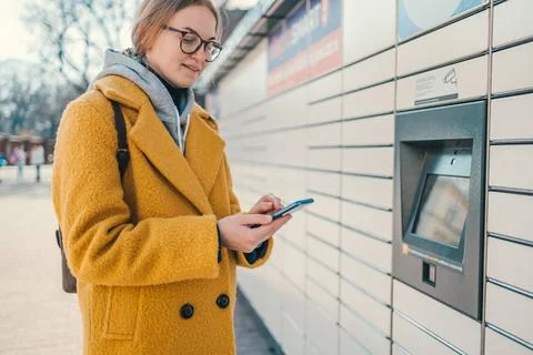 Self service post terminal machine and parcel sending. Woman holding smartphone Foto stock