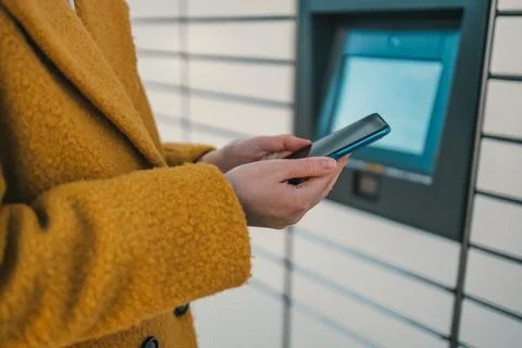 Self service post terminal machine and parcel sending. Woman holding smartphone Stock Photos