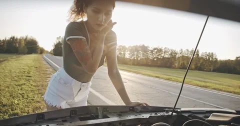 Self-sufficient confident modern young woman checking level of the engine oil in Stock Footage 115151750