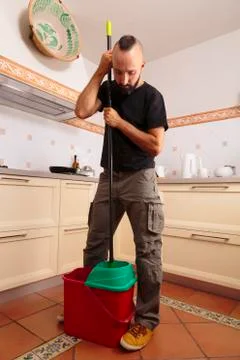 Self-sufficient young hispanic man squeezing the mop Stock Photos