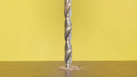 A self-tapping screw in a wooden block on a yellow background. Screwdriver screw Stock Footage 253111469