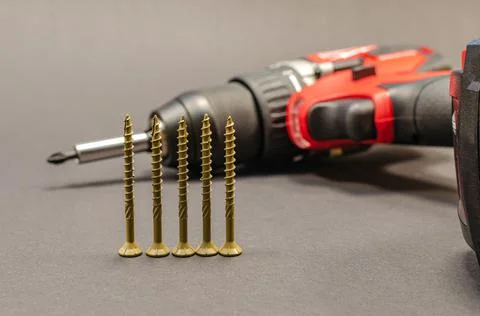 Self-tapping screws on the background of a battery screwdriver, a selection o Stock Photos