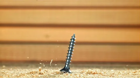 Self-tapping screws fall on a wooden surface. Filmed on a high-speed camera at Stock Footage 307928949