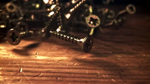 Self-tapping screws fall on a wooden table. Filmed on a high-speed camera at Stock Footage 307932202