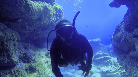 Selfie camera view of a scuba diver wearing diving gear swimming through a under Stock Footage 313756973