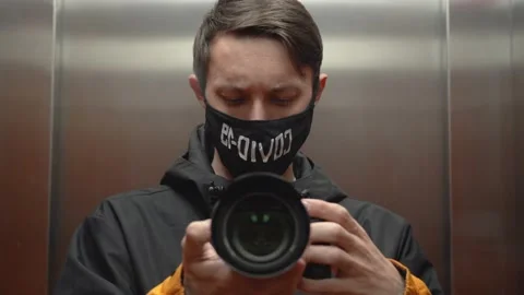 Selfie of one young man in elevator. Guy wearing face mask, inscription Covid-19 스톡 동영상 131476850