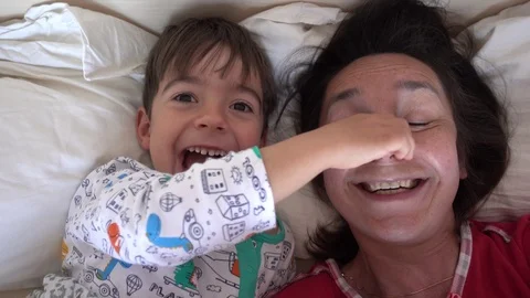 Selfie son drags away his mothers nose in the bed, Crystal child Stock Footage 88544991