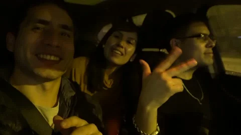Selfie of three friends singing and driving in a moving car on a night out and Video stock 160989691
