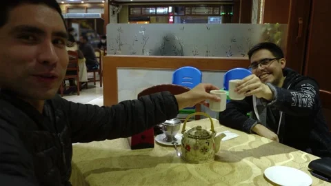 Selfie of two friends toasting tea in a restaurant smiling and talking Stock Footage 161445862