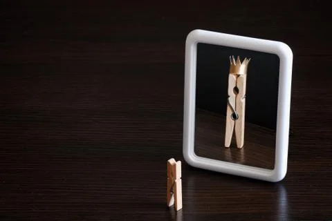 Selfish concept. small clothespin seeing himself in the mirror as big king wi Stock Photos