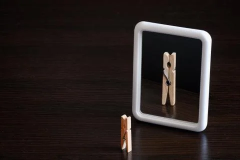 Selfish concept. small clothespin seeing himself in the mirror as big king wi Stock Photos