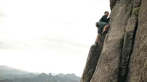 A selfless man climbs to the top of the cliff without a rope. Video stock 92609851