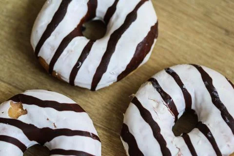 Selfmade vanilla donuts on table. The donuts have white glaze with brown choc Stock Photos