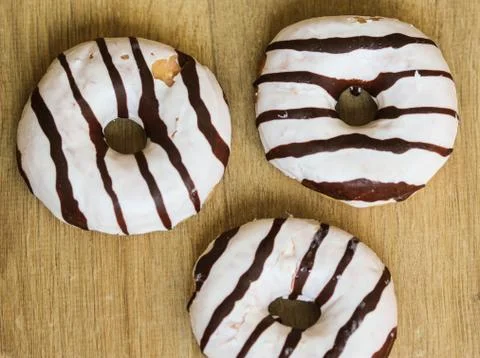 Selfmade vanilla donuts on table. The donuts have white glaze with brown choc Stock Photos