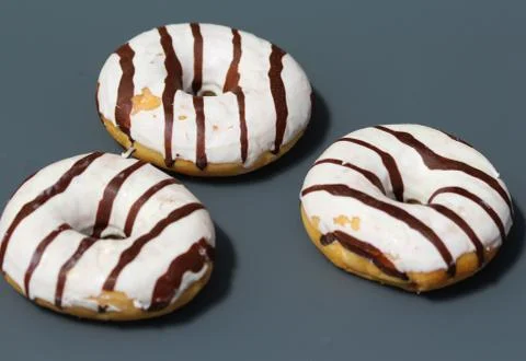 Selfmade vanilla donuts on table. The donuts have white glaze with brown choc Stock Photos