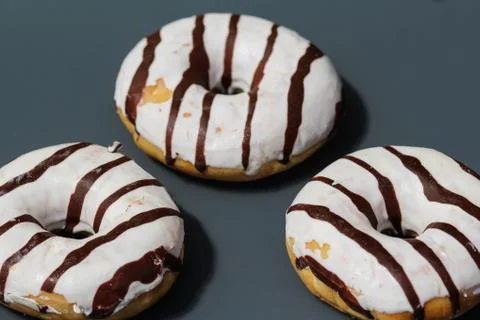 Selfmade vanilla donuts on table. The donuts have white glaze with brown choc Stock Photos
