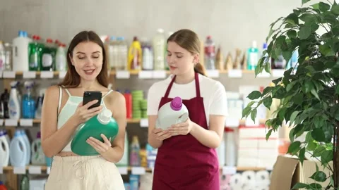 Seller offers detergent to the customer while she scans the barcode of the Stock Footage 341531514