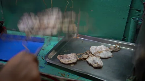 Seller preparing dry squids for grilling on street side of Thailand snack f.. Video stock 229923975