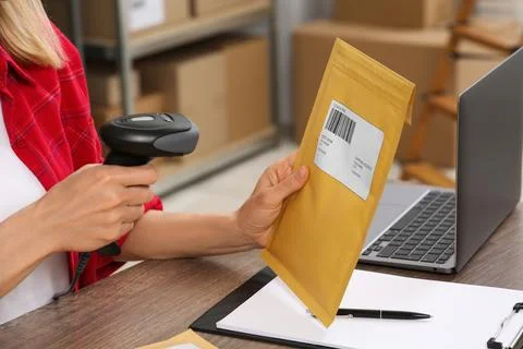 Seller with scanner reading parcel barcode at table in office, closeup. Onl.. Stock-Fotos