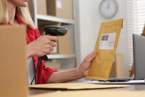 Seller with scanner reading parcel barcode at table in office, closeup. Onl.. Photos
