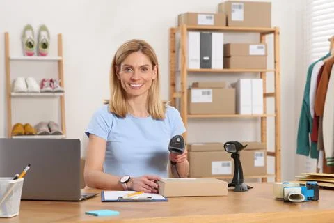 Seller with scanner reading parcel barcode at table in office. Online store Stock-Fotos