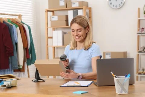 Seller with scanner reading parcel barcode at table in office. Online store Stock-Fotos