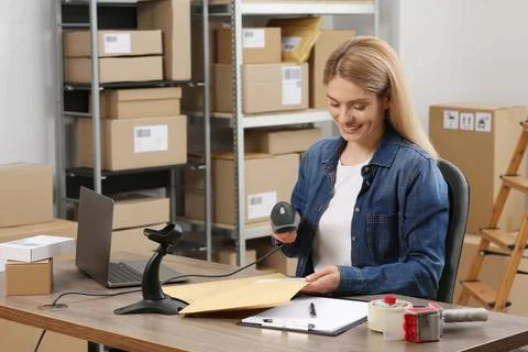 Seller with scanner reading parcel barcode at workplace. Online store Photos