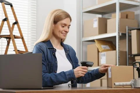 Seller with scanner reading parcel barcode at workplace. Online store Photos