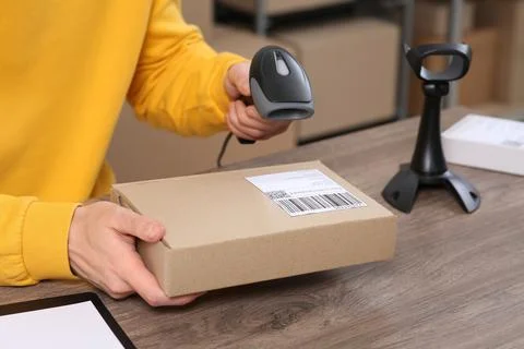 Seller with scanner reading parcel barcode at workplace, closeup. Online stor Photos