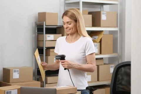 Seller with scanner reading parcel barcode at workplace. Online store Photos