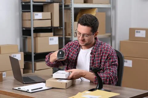 Seller with scanner reading parcel barcode at table in office. Online store Stock-Fotos