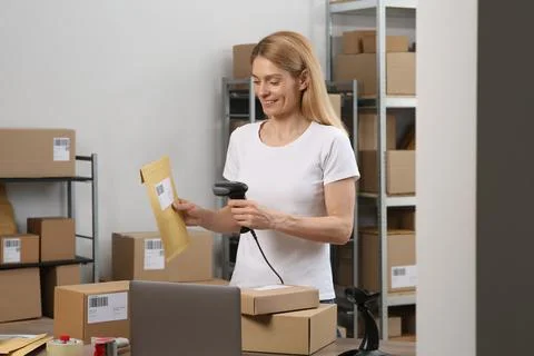 Seller with scanner reading parcel barcode at workplace. Online store Photos