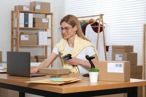 Seller with scanner reading parcel barcode in office. Online store Stock Photos