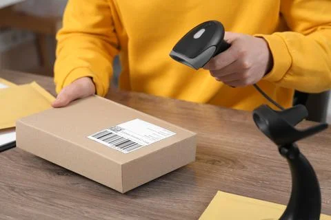 Seller with scanner reading parcel barcode at workplace, closeup. Online stor Photos