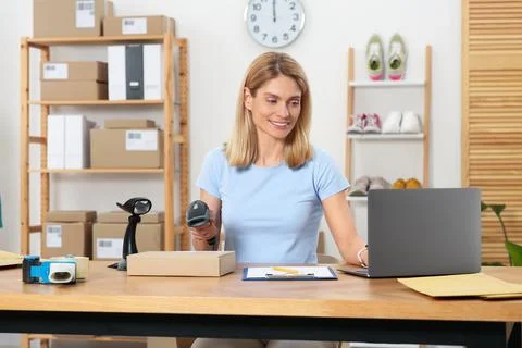 Seller with scanner reading parcel barcode at table in office. Online store Stock-Fotos