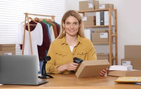 Seller with scanner reading parcel barcode at table in office. Online store Stock-Fotos