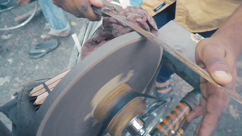 Seller sharpening knife using grinder in streets near KR market, in slow motion Stock Footage 93886161