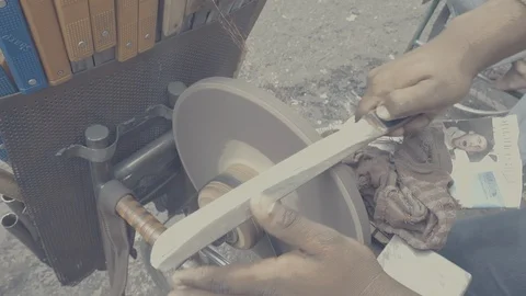 Seller sharpening knife using grinder in streets near KR market, in slow motion Stock Footage 93886548